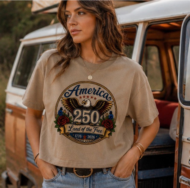 Woman wearing a t-shirt with an eagle graphic and text, standing in front of a vintage van.