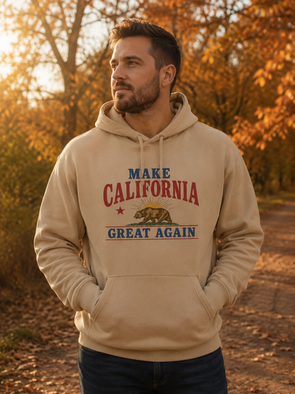 A man wearing a beige pullover hoodie with a 'MAKE CALIFORNIA GREAT AGAIN' graphic in red and blue, standing on an autumn path with golden trees in the background.