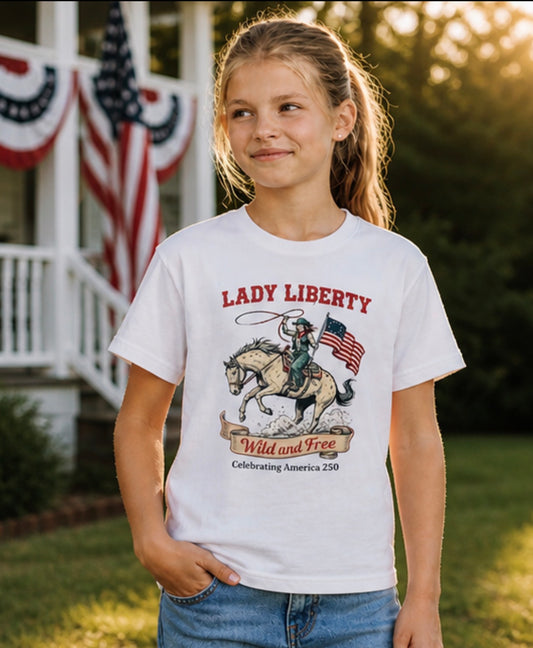 Young girl wearing a 'Lady Liberty' t-shirt with a horse and American flag design, standing outdoors.