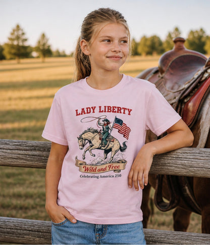Young girl wearing a 'Lady Liberty' t-shirt with a horse and flag design, standing next to a horse in a field.