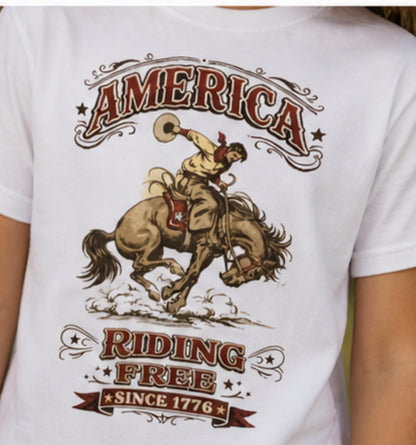 White t-shirt with a graphic of a cowboy riding a horse and text 'America Riding Free Since 1776' on a white background.
