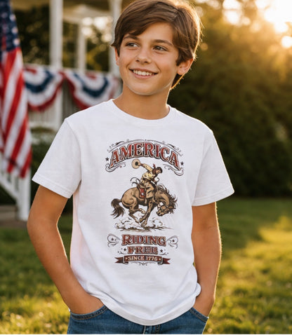 Child wearing a white t-shirt with a graphic design of a cowboy on a horse and text, standing outdoors with American flags in the background.