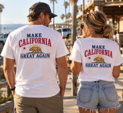 A man and a woman standing on a sunny boardwalk wearing matching white graphic t-shirts with the text 'MAKE CALIFORNIA GREAT AGAIN' and a California grizzly bear design on the back.