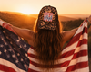 Person holding an American flag with a sunset in the background