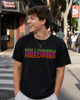 A young man smiling and looking to the side while wearing a black t-shirt with 'HALLOWEEN' printed across the chest in a green-to-purple-to-orange gradient. The background shows a blurred city street scene with a 'Record Archive' storefront.