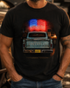 A man wearing a black graphic t-shirt featuring a distressed blue Chevrolet pickup truck with a glowing red, white, and blue American flag on its tailgate, set against a blurred outdoor background.