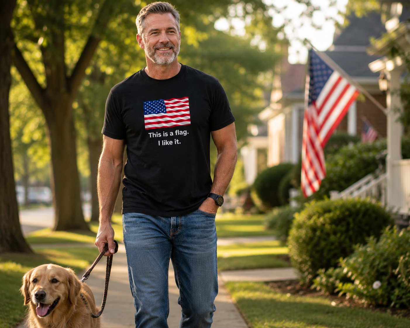 A man walking a golden retriever on a suburban sidewalk, wearing a black t-shirt with a graphic of the American flag and the text 'This is a flag I like it.'.