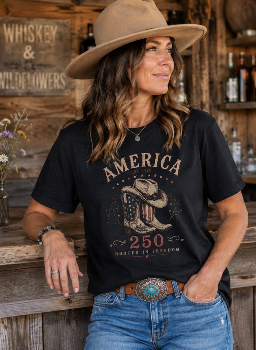 Woman wearing a black t-shirt with 'America 250' design in a rustic setting.