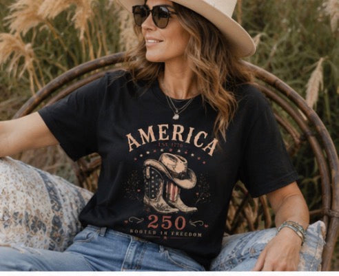 Woman wearing a black patriotic America 250 western T-shirt with a hat on