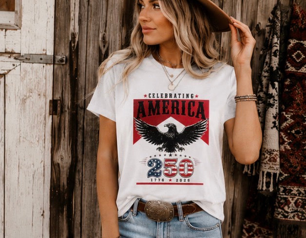 Woman wearing a t-shirt with an eagle graphic and text, standing in front of a wooden wall.
