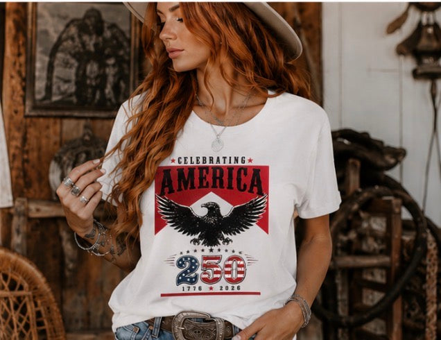 Woman wearing a white t-shirt with an eagle graphic and text in a rustic setting