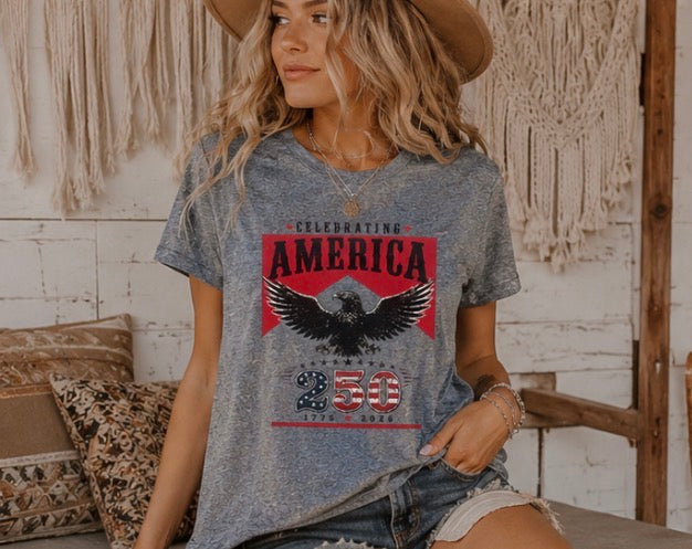 Woman wearing a t-shirt with 'Celebrating America 250' design in a casual setting.