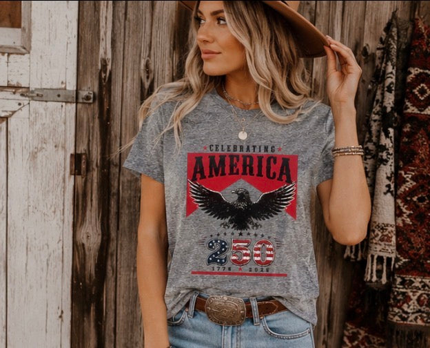 Woman wearing a gray t-shirt with an eagle graphic and text, standing against a wooden wall.