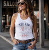 Woman wearing a white tank top with 'Yee Haw America 250' design, standing in front of a saloon.