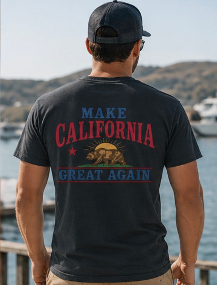 Person wearing a black t-shirt with 'Make California Great Again' text and bear graphic, standing by a waterfront.