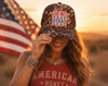 Woman wearing a cap with 'Oh My Stars' design and 'American Honey' shirt in front of an American flag.