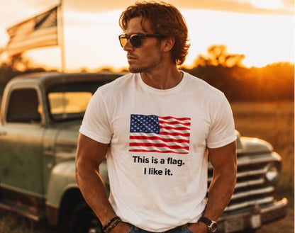 A man wearing a white graphic t-shirt with an American flag print and the text 'This is a flag. I like it.