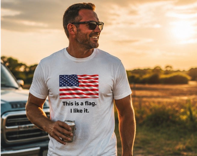 A man wearing a white graphic t-shirt with a printed American flag and the text 'This is a flag. I like it.