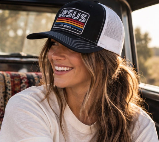 young woman wearing black trucker hat with jesus is king patch on the front 