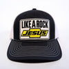 “Front view of black and white Like a Rock Jesus trucker hat with embroidered patch and white stitching on the bill.”