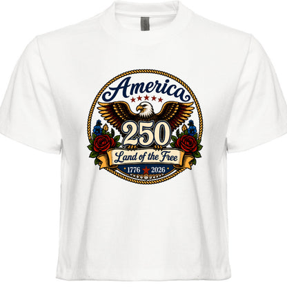 Women's white patriotic tee with vintage tattoo style circular graphic featuring golden eagle red roses gold rope border and America 250 Land of the Free 1776 to 2026 design
