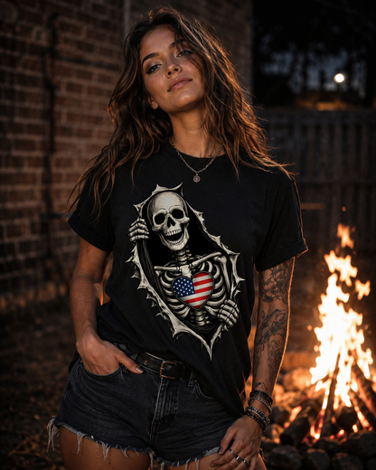 A woman wearing a black graphic t-shirt with a skeleton and American flag design, standing outdoors next to a burning campfire at night.
